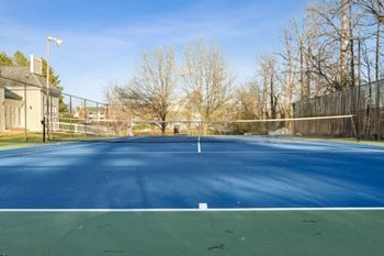 A tennis court with a fence around it on a sunny day